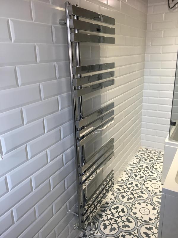 Chrome heated towel radiator installation on patterned Victorian floor tiles