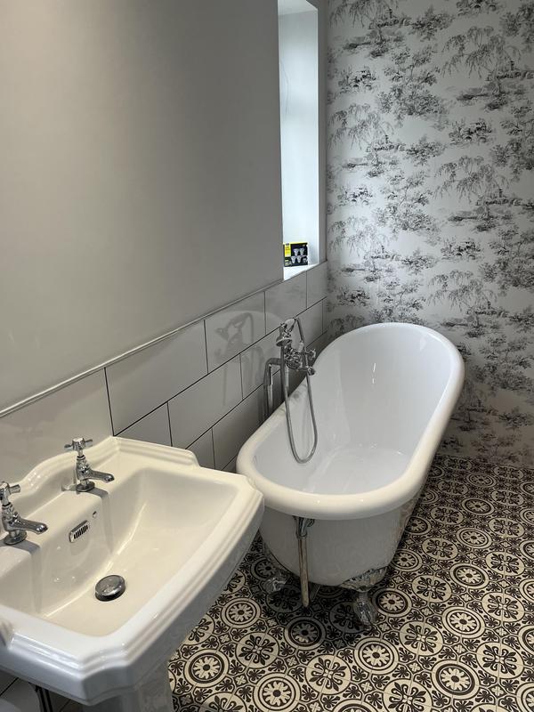 Finished period bathroom with roll-top clawfoot bath and patterned floor tiles