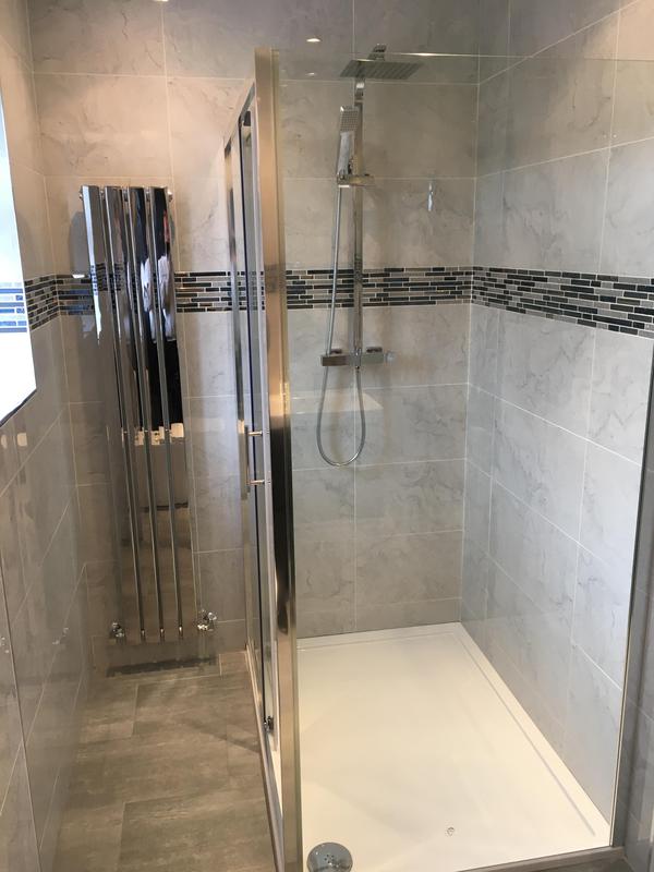 Walk-in shower installation with chrome rainfall head and marble-effect tiling
